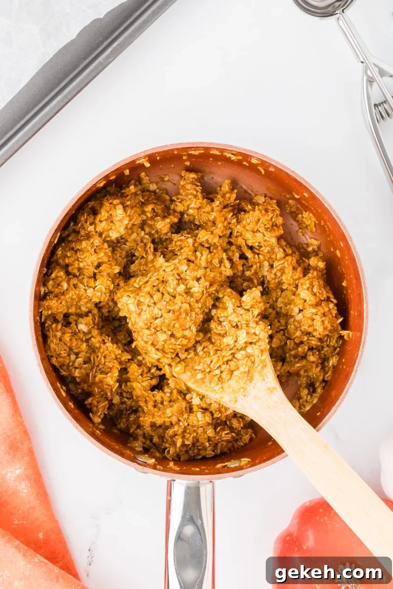 No-Bake Pumpkin Oat Cookies: Quick Fall Treats 7 Mixing oats into a wet mixture in a saucepan with a wooden spoon.
