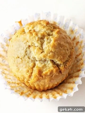 A single golden muffin on a white surface, open paper liner