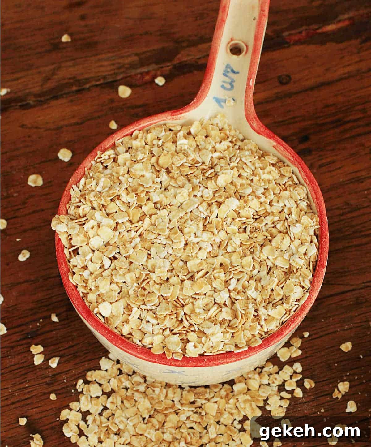 Ceramic measuring cup overflowing with oats on wooden table