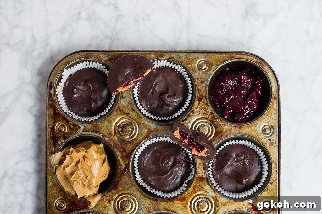 Muffin tin filled with chocolate peanut butter cups showing layers of jam and peanut butter.