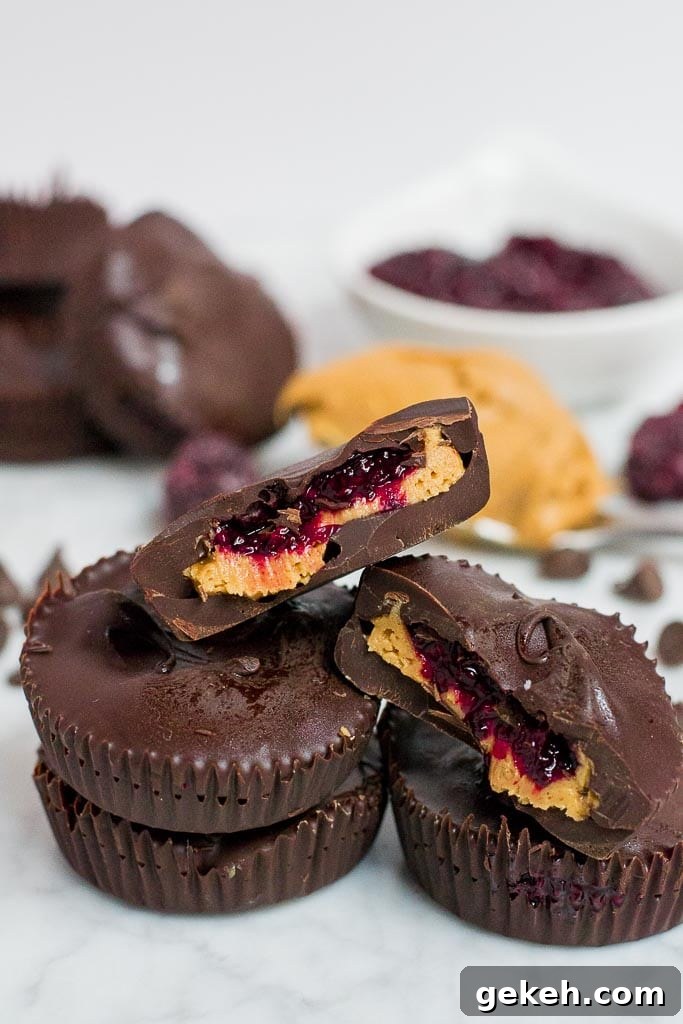 Stack of chocolate berry chia jam peanut butter cups, two cut open to show layers.