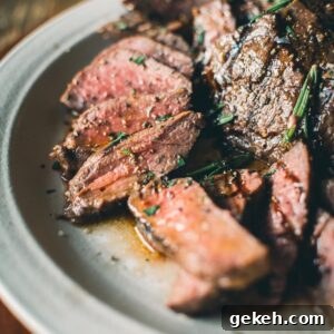 Grilled Elk Steaks: Juicy Elk Steak Recipe and Cooking Tips 12 A plate of sliced medium-rare elk steaks garnished with fresh rosemary is served on a table.