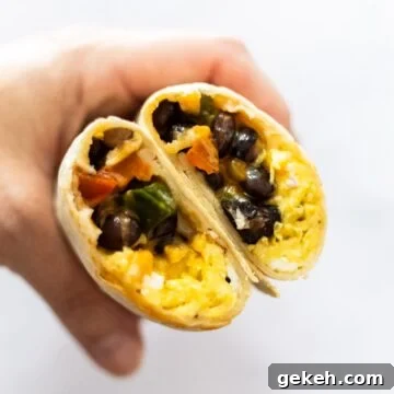 A side view of a halved breakfast burrito on a plate.