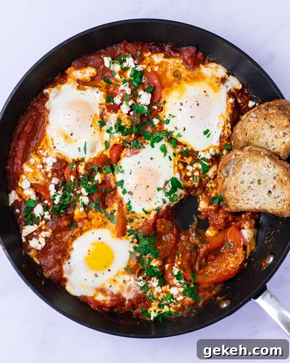 a top down view of a skillet of shakshouka with an egg missing.