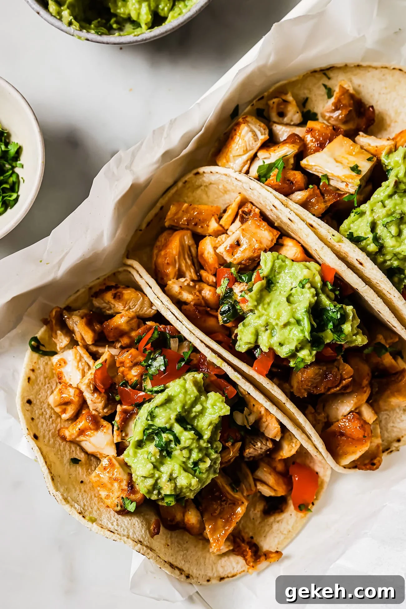 Chicken Tacos with Savory Homemade Marinade 2 An overhead view of three chicken tacos topped with Pico de Gallo and guacamole.