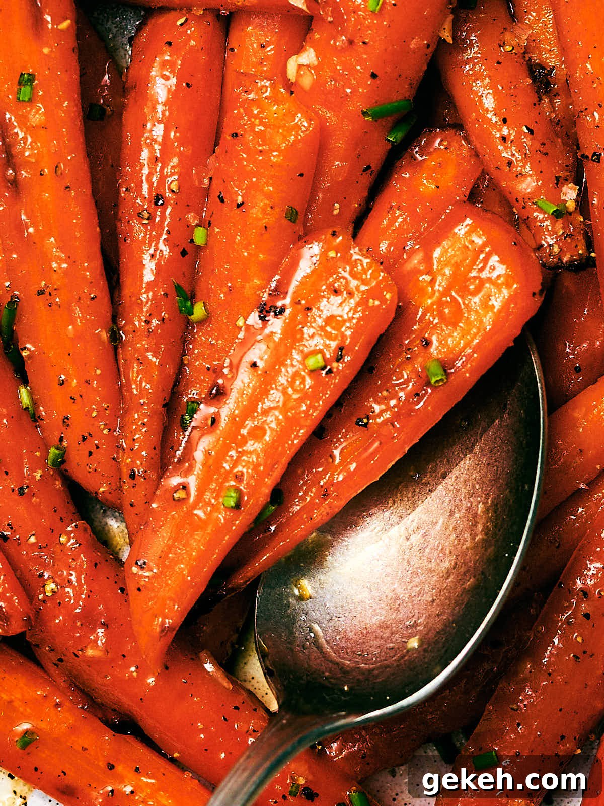 Honey Roasted Carrots with butter and chives being scooped with a spoon.