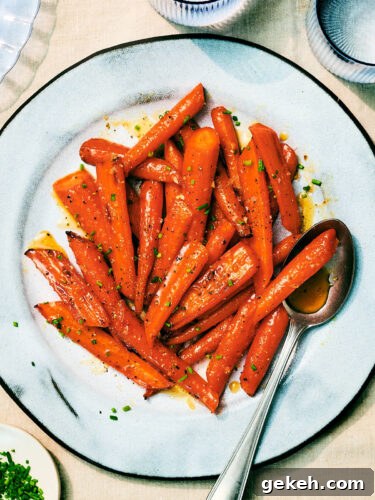 Air Fryer Honey Roasted Carrots with garlic and butter on a serving plate with a spoon.
