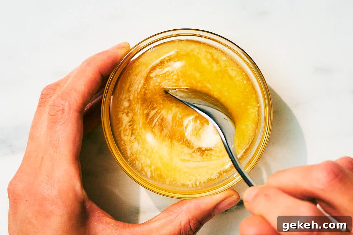 Melted butter and honey being stirred together in a glass bowl.