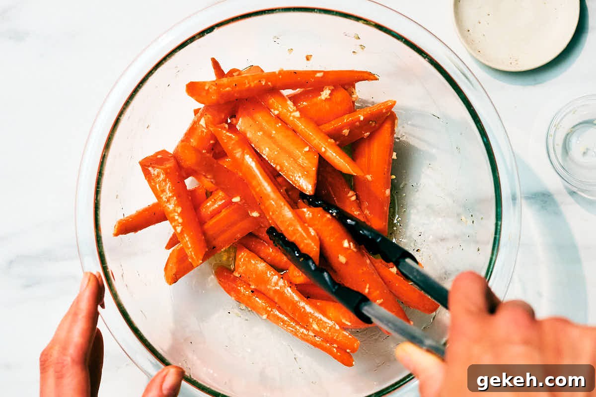Carrots being tossed with honey, butter, and garlic in a glass bowl.