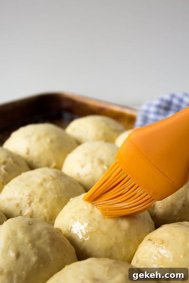 Soft Oatmeal Dinner Rolls Recipe for Fluffy Homemade Rolls 4 Brushing butter on uncooked rolls.