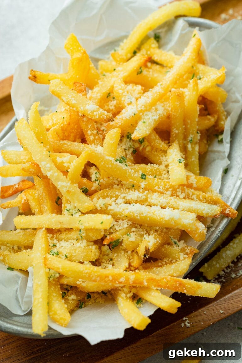 How to Make Disneyland-Style Pomme Frites at Home 4 a photo of a pile of golden hot salt pomme frites topped with parmesan cheese.
