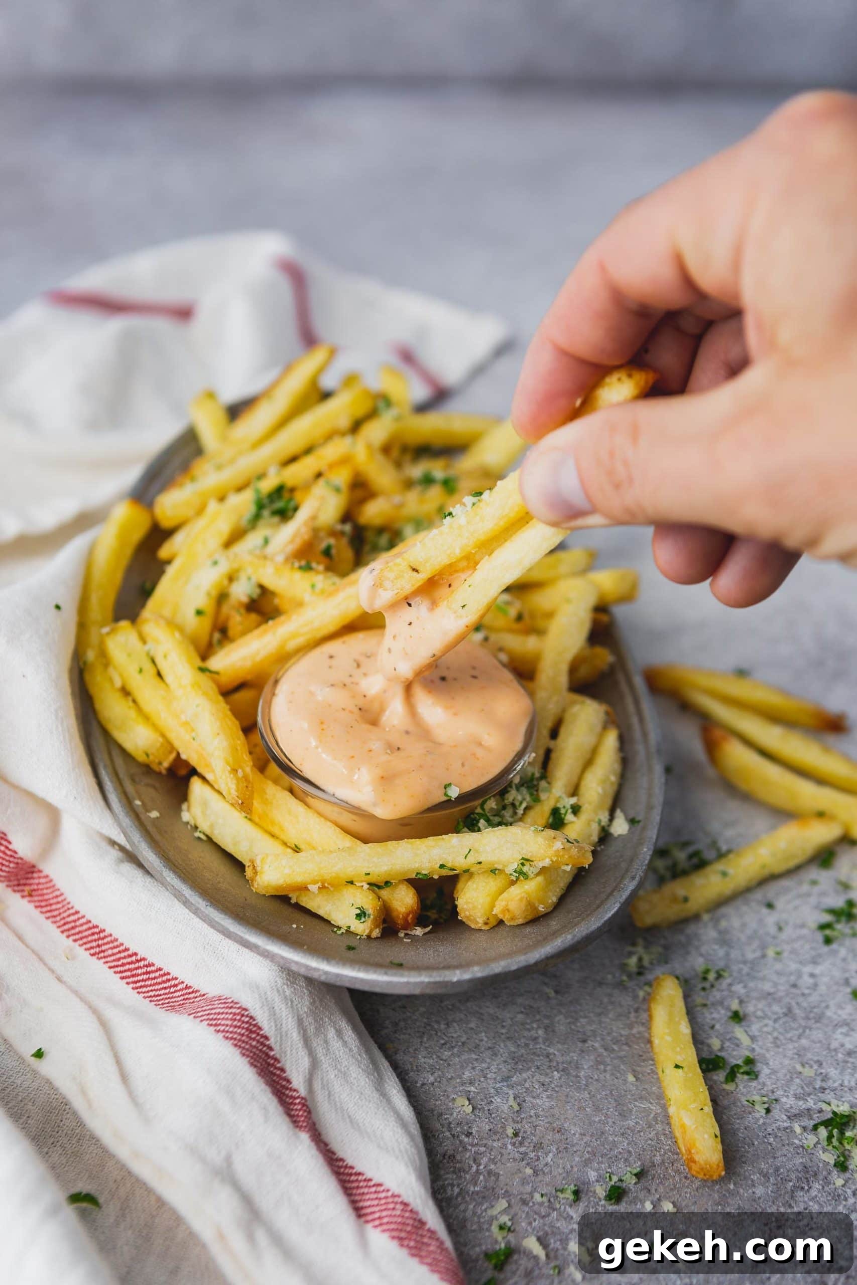 Disneyland's Pomme Frites Dipping Sauce Cajun Remoulade a photo of a plate of golden pomme frites with a cup of cajun dipping sauce with someone dipping two fries in it.