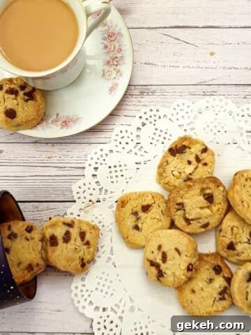 Chocolate chip and brazil nut cookies on a doily next to a cup of tea.