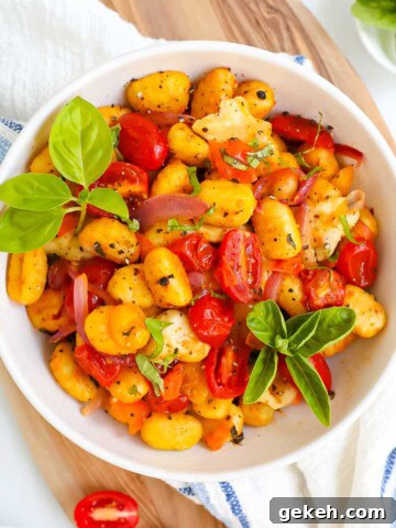 A bowl filled with gnocchi, vegetables, and basil.