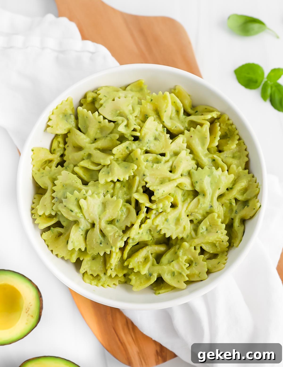 Bowtie pasta covered in a green sauce in a white bowl.
