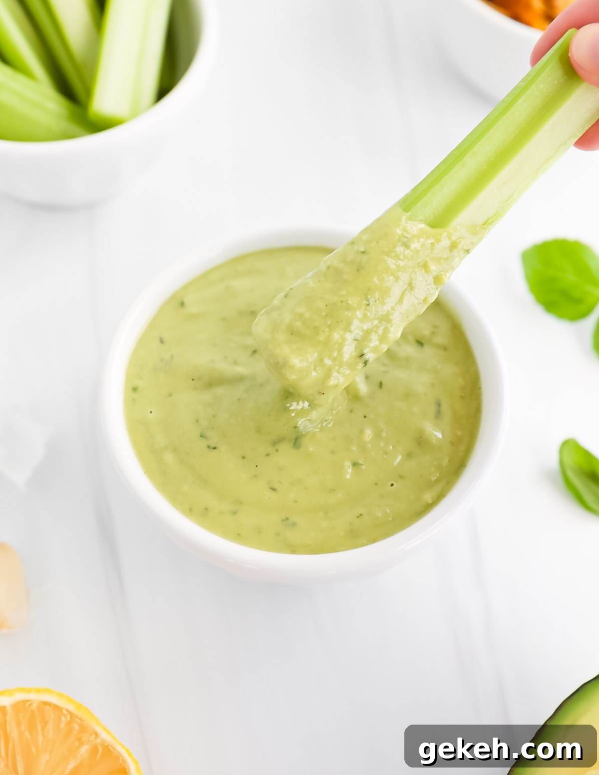 A piece of celery covered in a green creamy sauce.