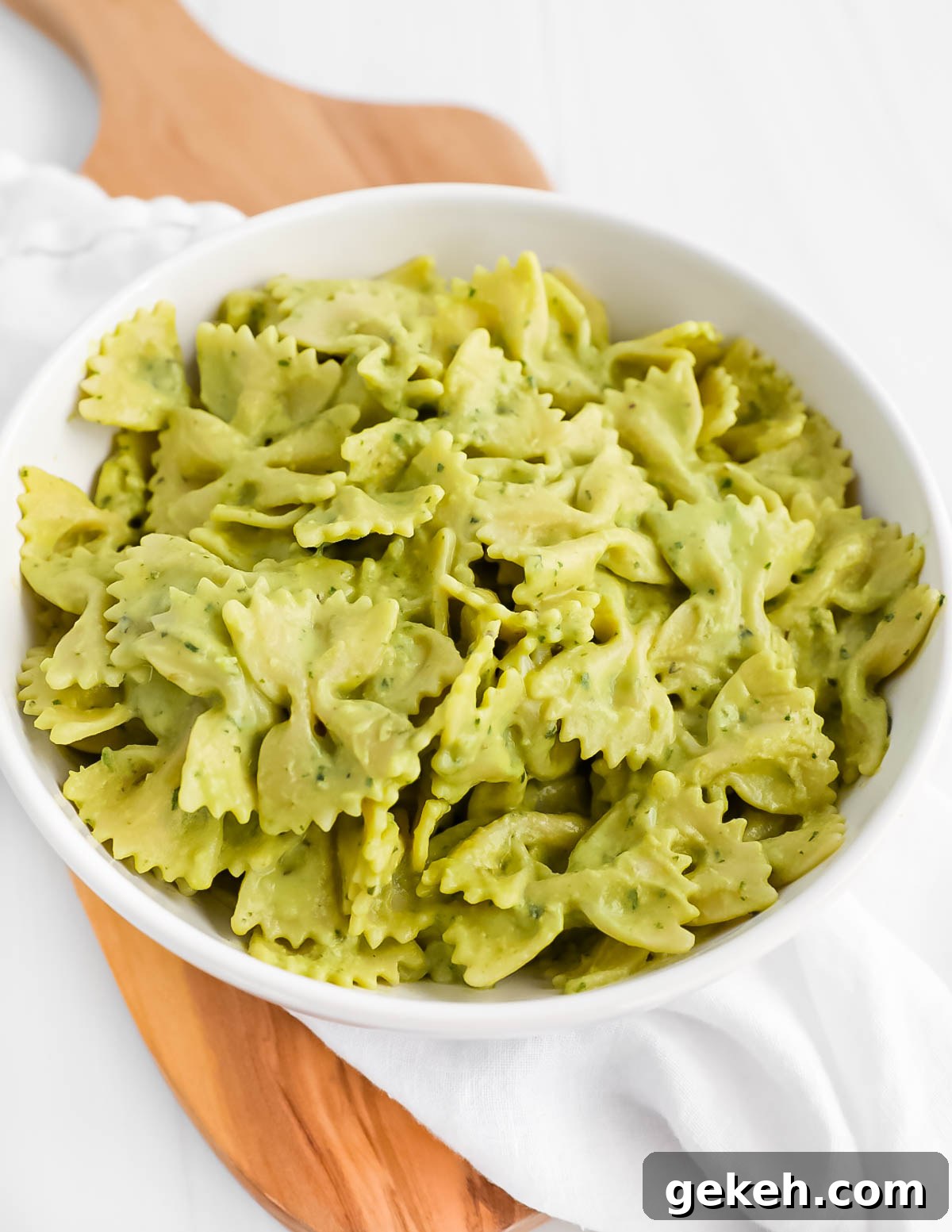A bowl of bowtie pasta covered in a green cream sauce.
