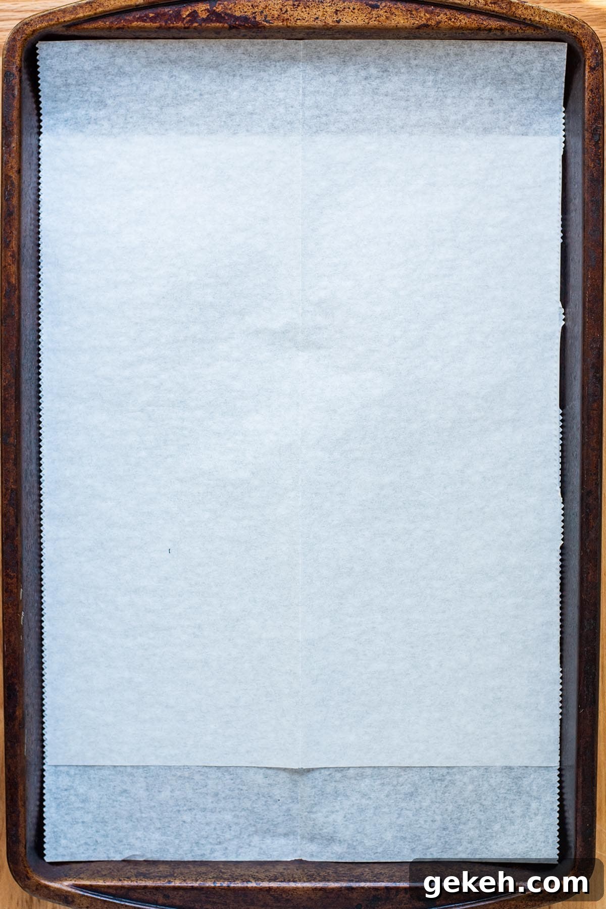 Perfectly Crispy Oven-Baked Bacon: Simple Sheet-Pan Method 3 A rimmed baking sheet lined with white parchment paper.