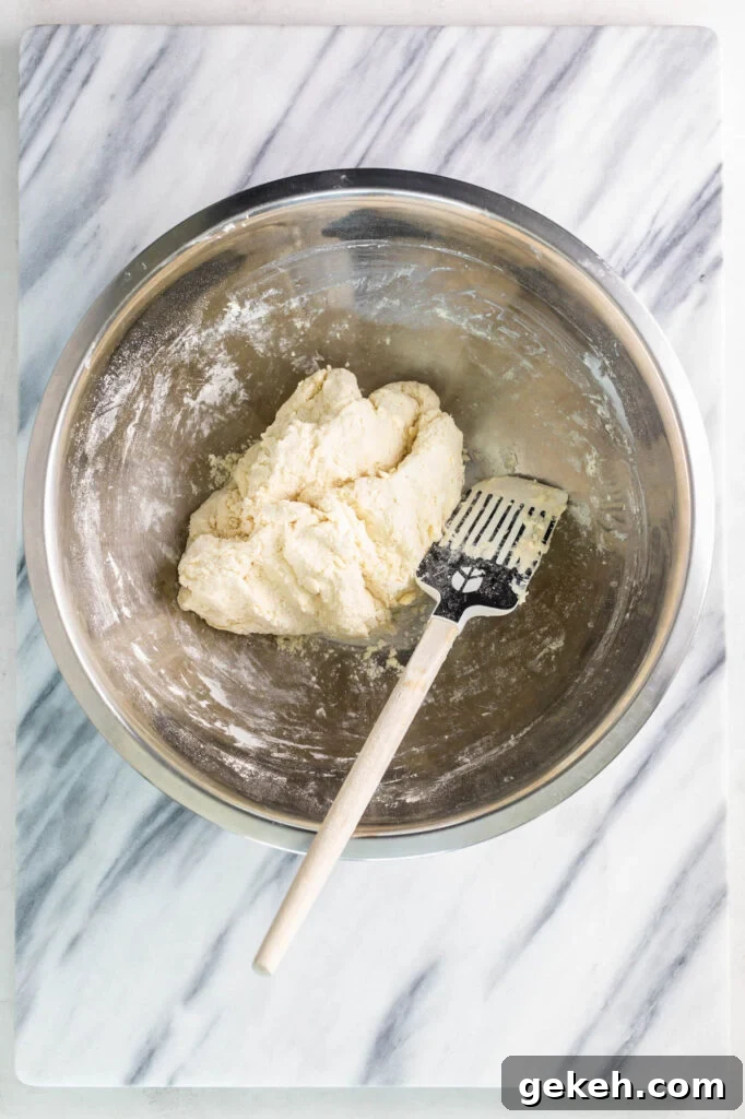 forming old fashioned buttermilk biscuits dough in a mixing bowl with a spatula
