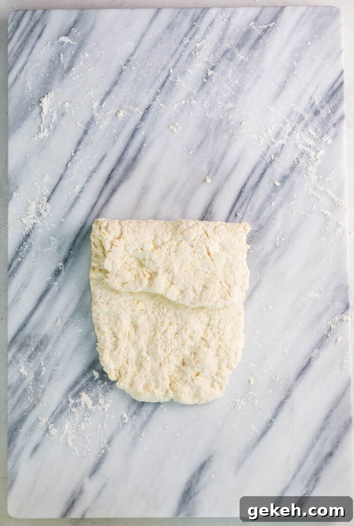 folding old fashioned buttermilk biscuits dough on floured marble slab