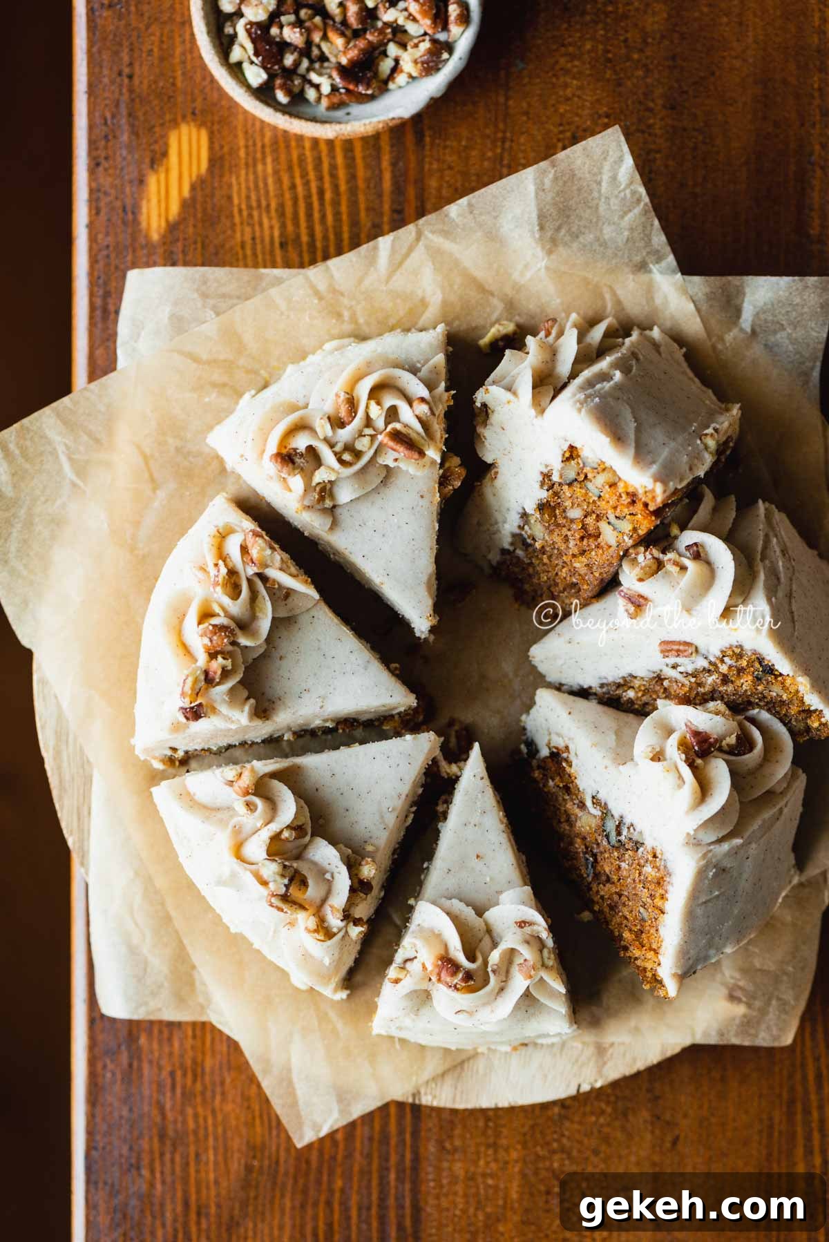 Overhead image of single layer carrot cake frosted on parchment paper and placed on a wood dining room table | All Images © Beyond the Butter®
