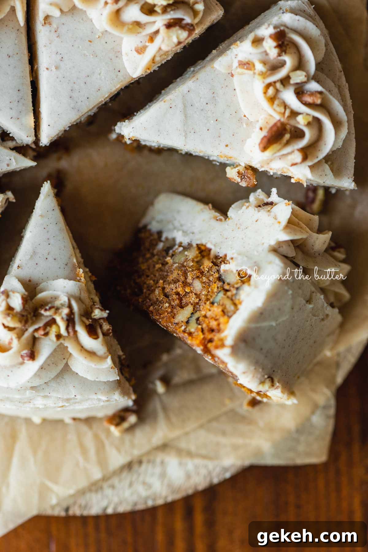 Overhead closeup image of single layer carrot cake frosted on parchment paper and placed on a wood dining room table | All Images © Beyond the Butter®
