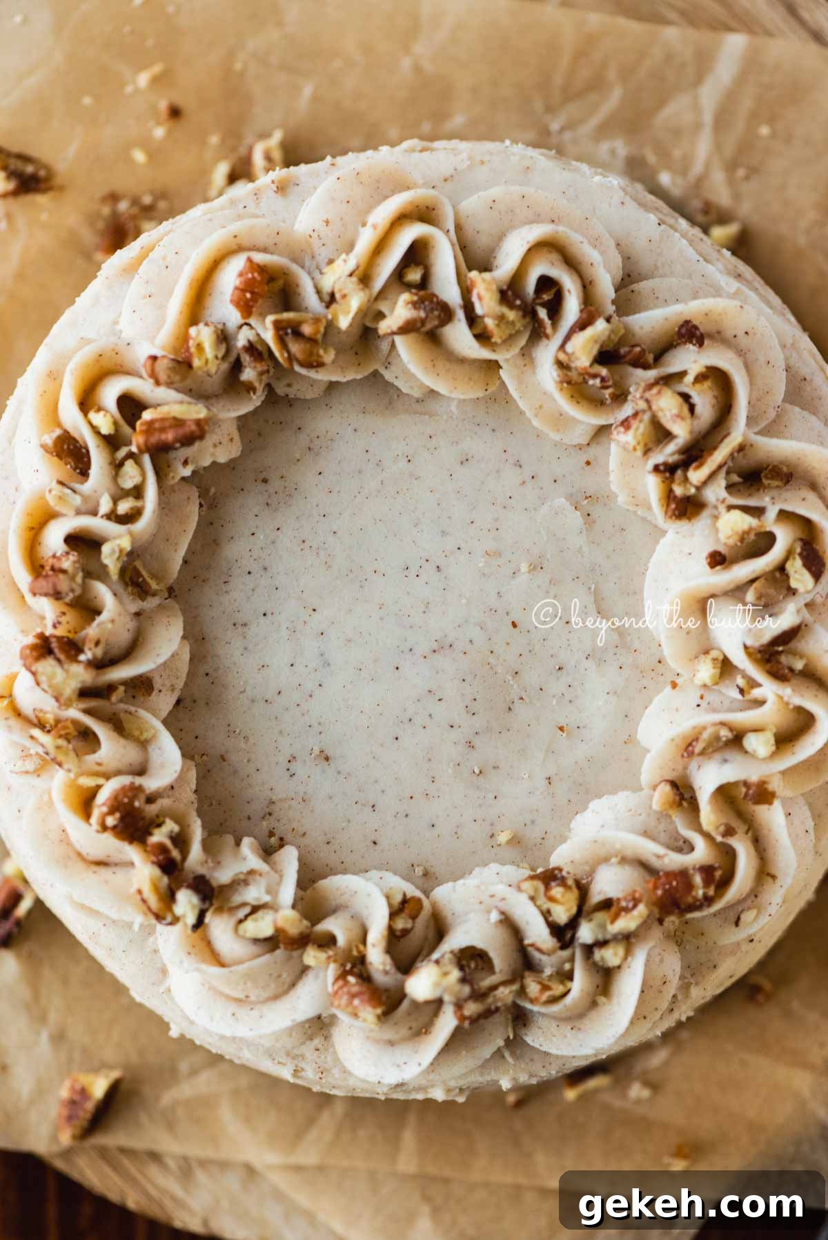 Overhead closeup image of 6 inch carrot cake frosted on sheets of brown parchment paper | All Images © Beyond the Butter®