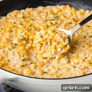 A skillet filled with honey butter corn. A large spoon is in the middle.