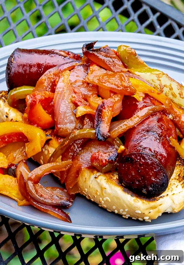 Grilled Sausage with Peppers and Onions on a bun on a gray plate