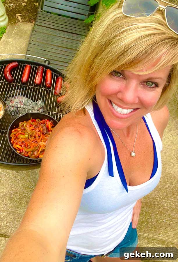 Jennifer with weber grill behind grilling sausages, onions, and peppers