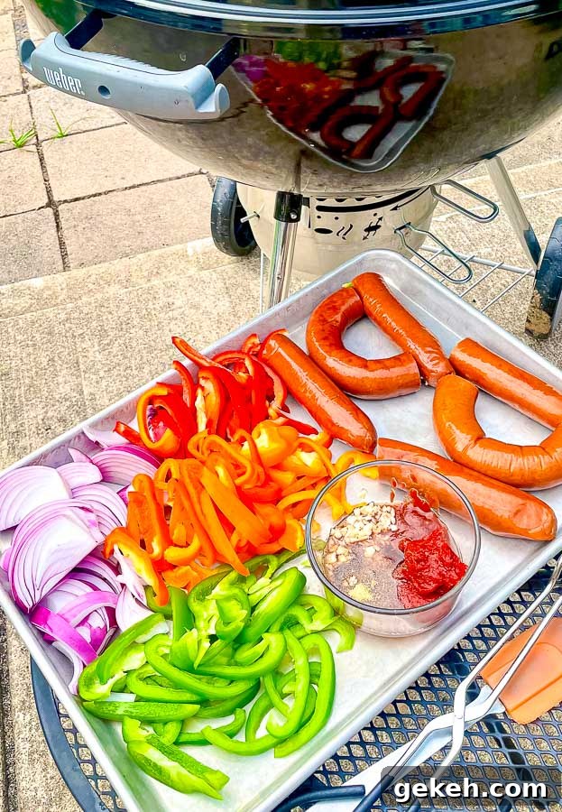 ingredients for grilled sausage with onions and peppers next to a weber grill