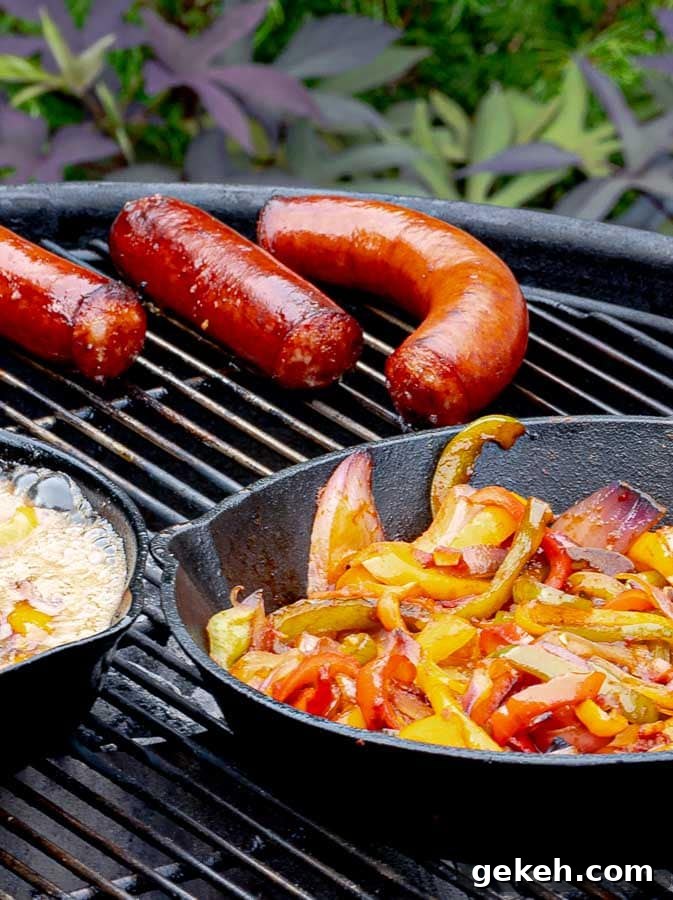 sausages and a cast iron skillet of onions and peppers on the grill