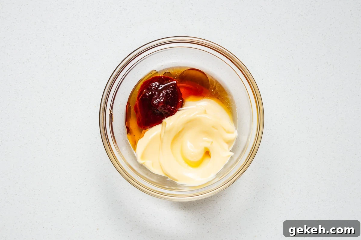 Spicy Gochujang Mayonnaise Sauce Recipe 5 The ingredients for spicy Korean mayonnaise in a small glass bowl including kewpie mayo, gochujang, toasted sesame oil, rice vinegar and maple syrup.
