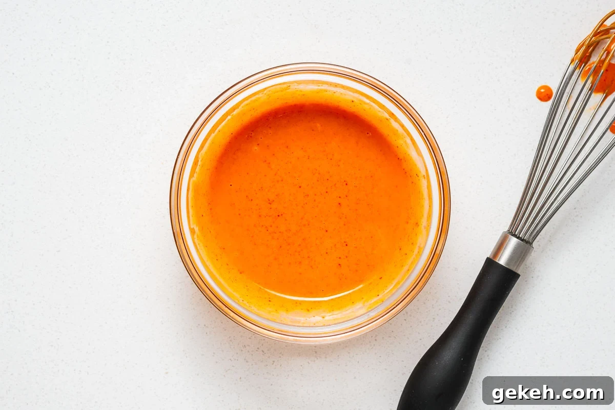 Spicy Gochujang Mayonnaise Sauce Recipe 6 A small glass mixing bowl with gochujang mayonnaise next to a used whisk.