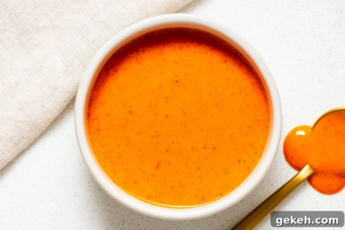 Spicy Gochujang Mayonnaise Sauce Recipe 7 A white ceramic bowl with spicy Korean mayo sauce next to a golden spoon.