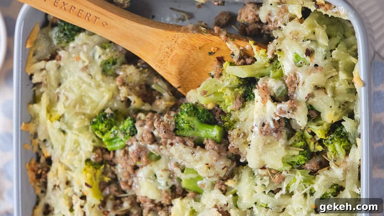 15 Sophisticated Dinner Ideas to Impress with Minimal Effort 12 A baked casserole dish with ground beef and broccoli casserole and a wooden spoon.