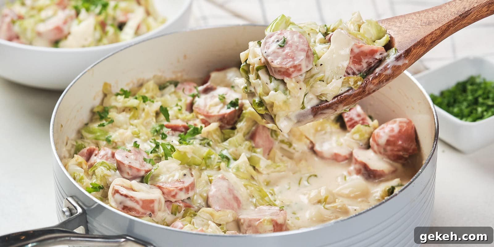 15 Sophisticated Dinner Ideas to Impress with Minimal Effort 14 A skillet containing a creamy cabbage and sausage alfredo garnished with herbs.
