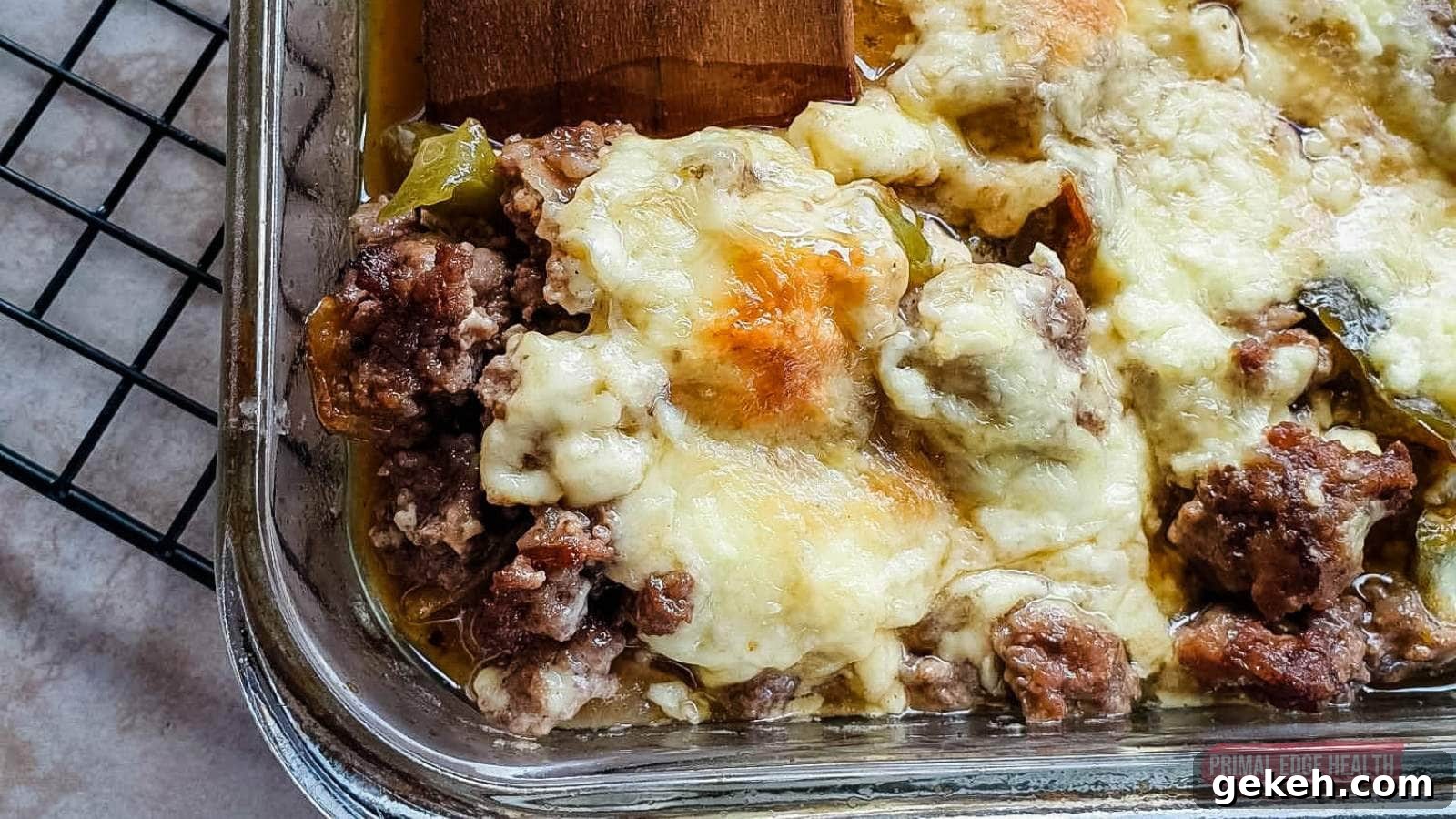 15 Sophisticated Dinner Ideas to Impress with Minimal Effort 9 Image shows a wooden spatula cutting philly cheesesteak casserole from baking dish.