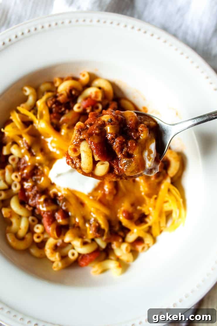 Chili Mac Recipe: Classic Comfort Pasta with Savory Beef and Beans 2 Chili mac on spoon above bowl.