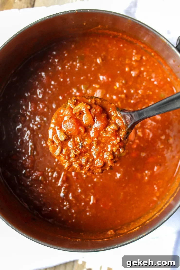 Chili Mac Recipe: Classic Comfort Pasta with Savory Beef and Beans 5 Spoonful of chili above pot.