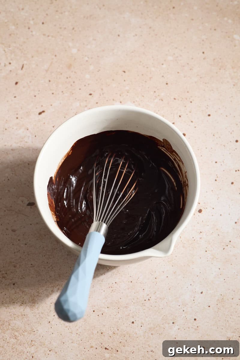 Chocolate mixture in a small bowl with a whisk.