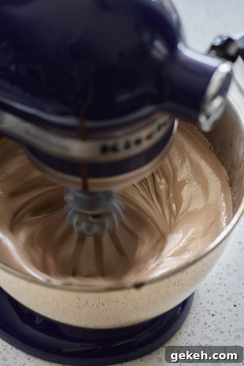 Marshmallow being whipped in the bowl of a stand mixer.