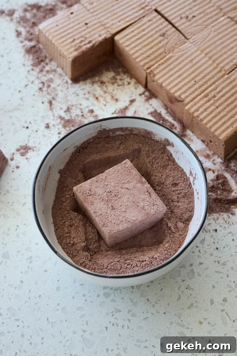 Marshmallow being rolled in the powdered sugar mixture.