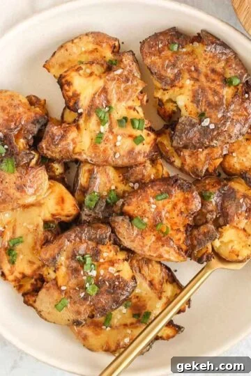 Fried smashed potatoes on a round serving plate with a gold fork.