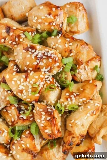 Pieces of air fried teriyaki chicken on a white plate.