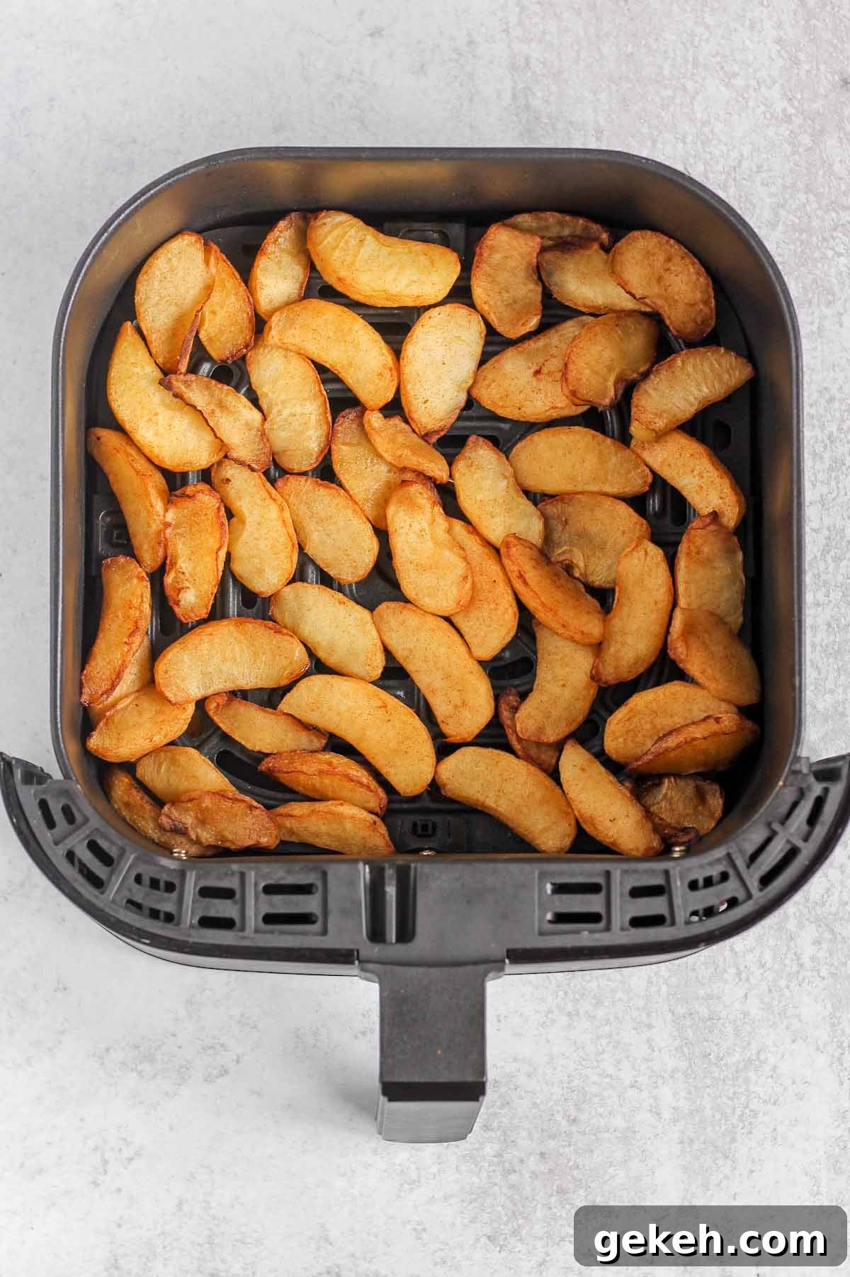 Air fried apples in an air fryer basked right after being air fried.