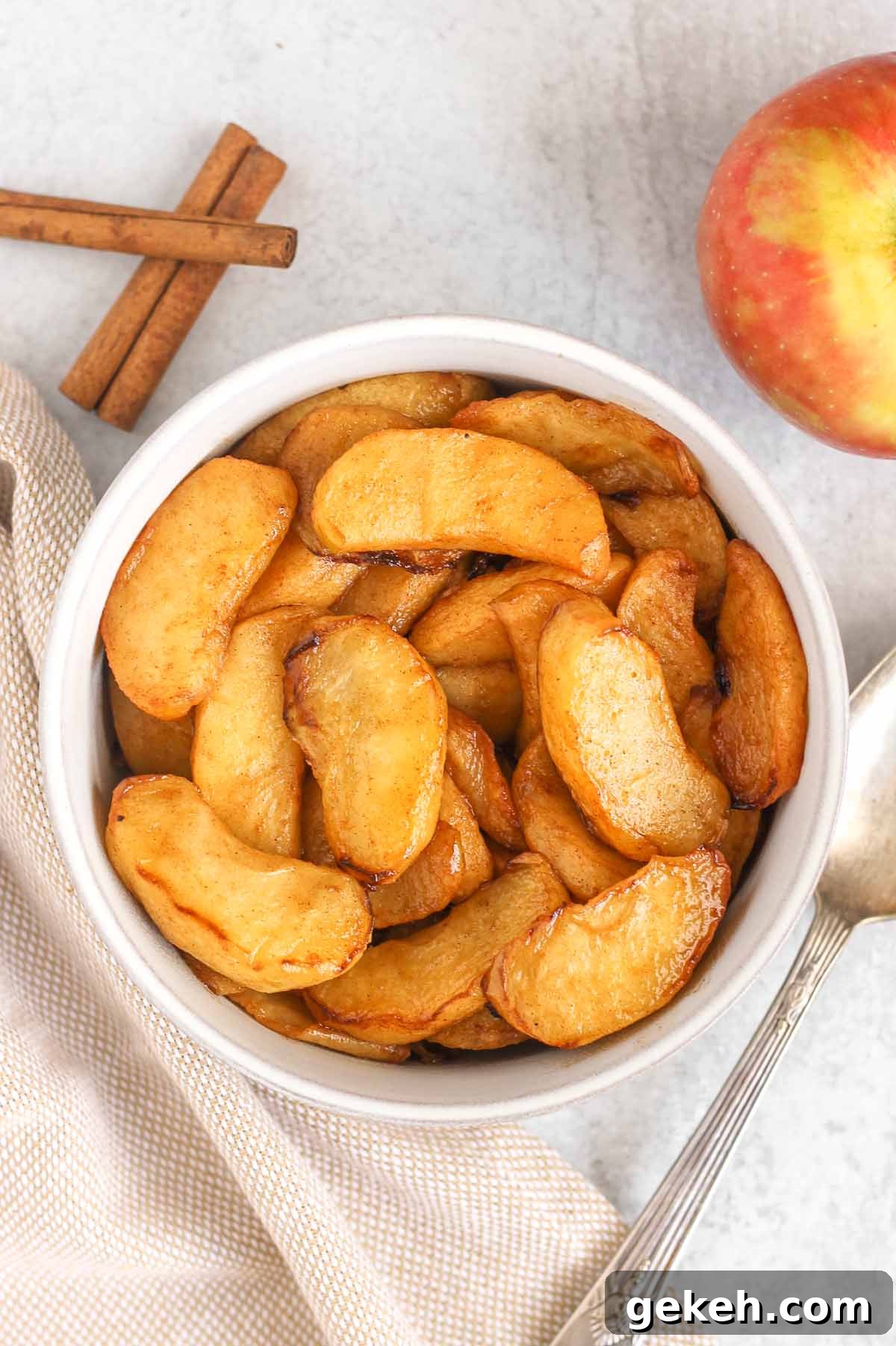 Air fried apples in a serving bowl with a tan linen napkin and vintage spoon next to the bowl.