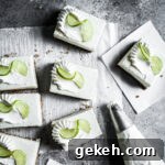 No-Bake Key Lime Cheesecake Bars Recipe for Zesty Dessert 9 Squares of white cheesecake bars on parchment paper on a grey stone surface